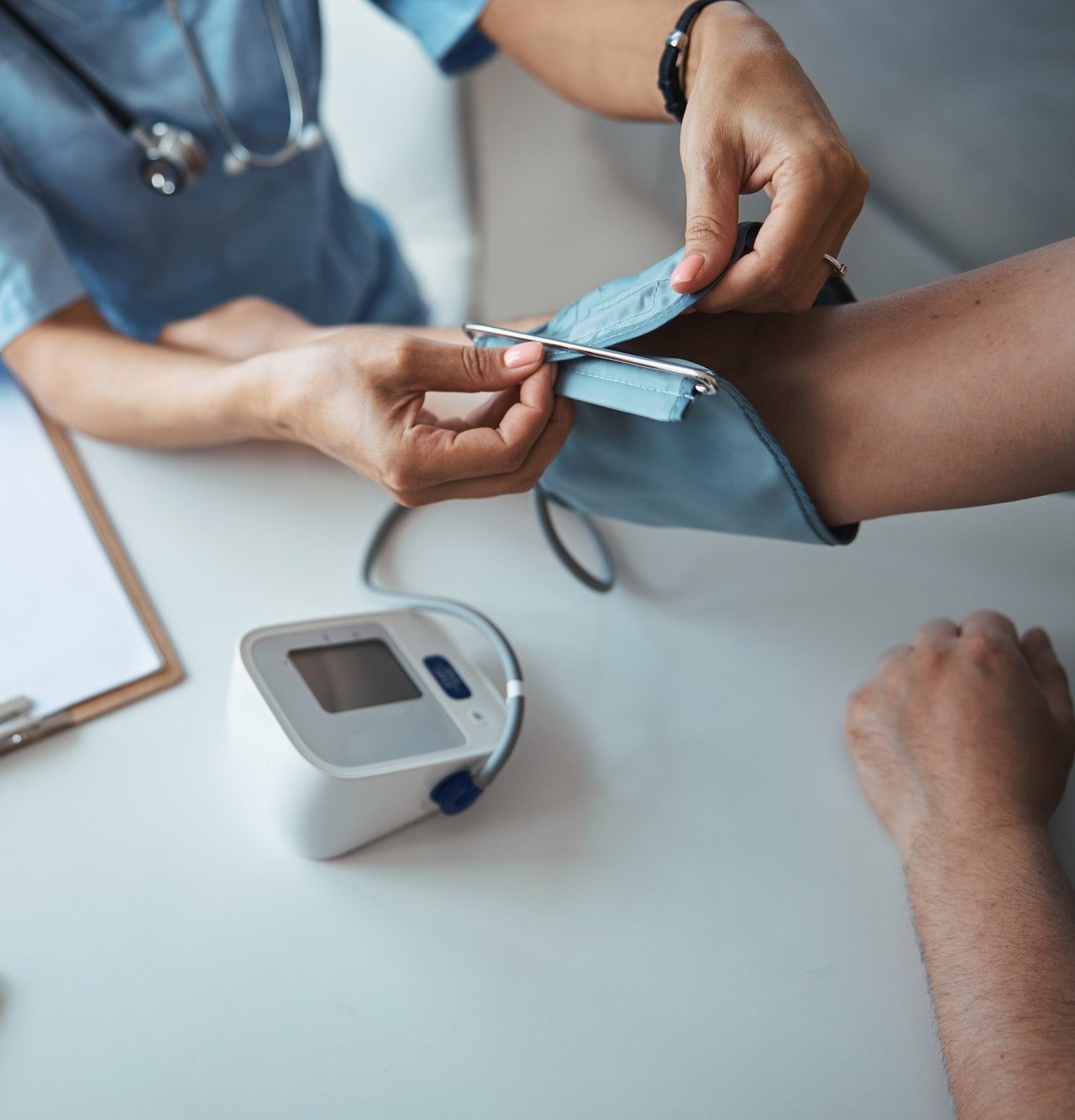 A healthcare professional is measuring a patient's blood pressure using a digital monitor. The setting appears to be a medical office.